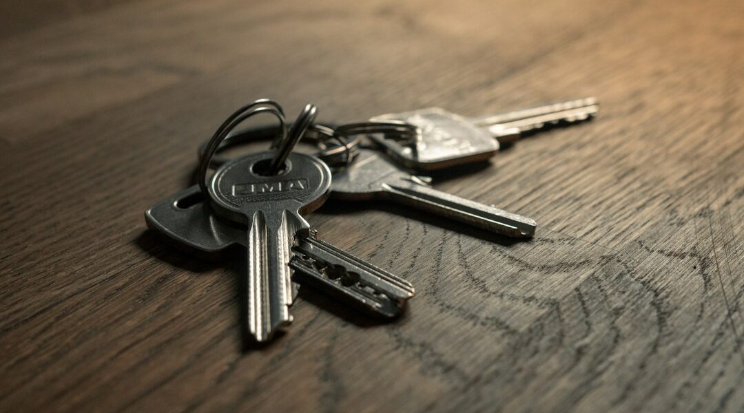 A close-up of a set of metal keys resting on a wooden surface.